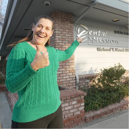 Woman pointing at her bright smile after cosmetic dental care.