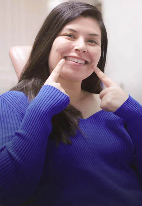 Woman pointing at her bright smile after cosmetic dental care.