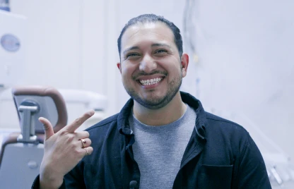 Happy patient pointing at his teeth after pain relief from root canal therapy.